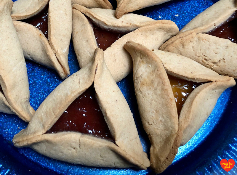 Close up of strawberry and apricot Hamantaschen on blue plate. 