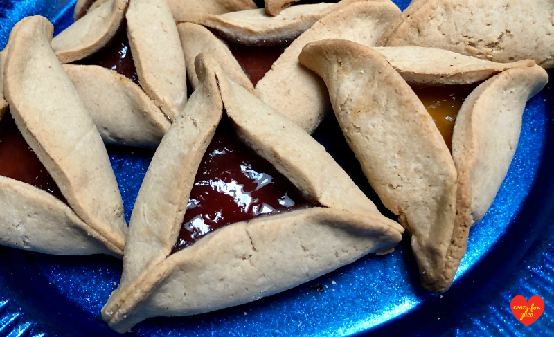 Close up of strawberry and apricot Hamantashen on blue plate.
