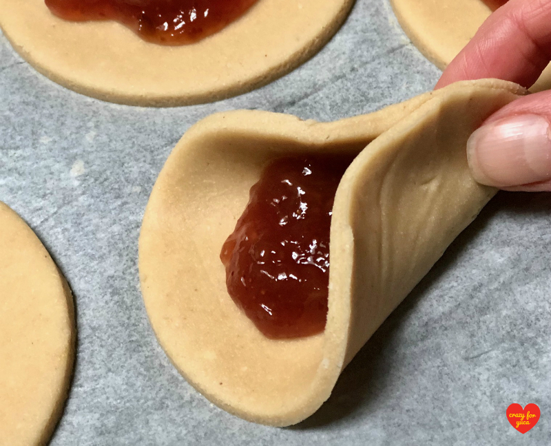 To make Hamantaschen into triangles, lift then pinch together one end of a rolled-out dough circle to make the first corner. 