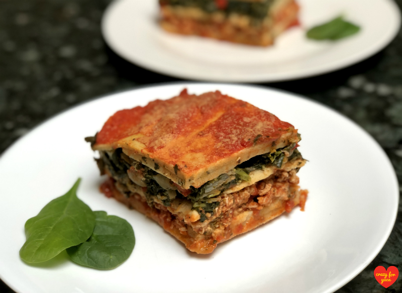 CrazyForYuca.com - a "real food" gluten and dairy-free recipe blog and place for all things yuca / cassava. Cassava Flour Pasta Lasagna on white plate with a second plateful in the distance. 