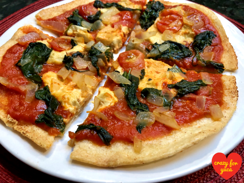 Paleo Yuca Pizza with Vegan Cheese cut into 4 slices on white plate.